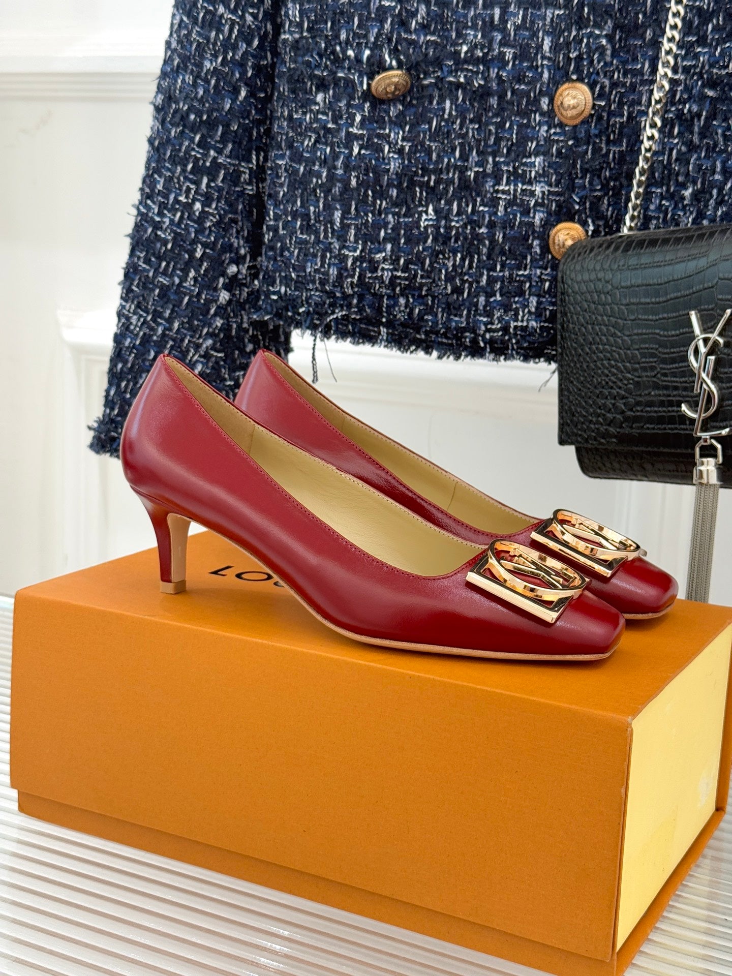 Louis Vuitton ladies red pumps with gold LV emblem at front, on orange display box
