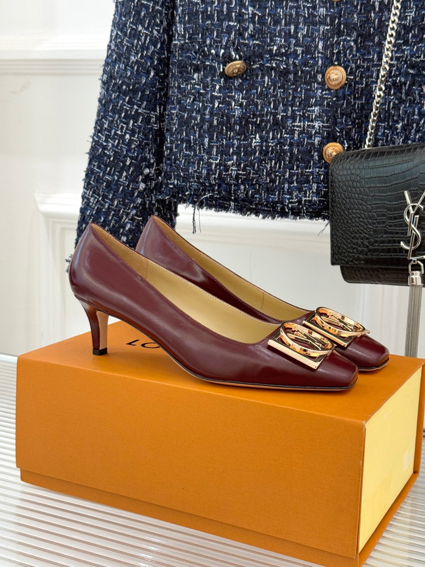 Burgundy leather low-heel pumps with gold logo square buckle detail.