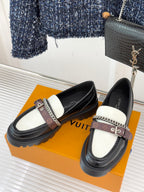 Pair of black loafers with white panels, chain strap, and thick rubber lug sole