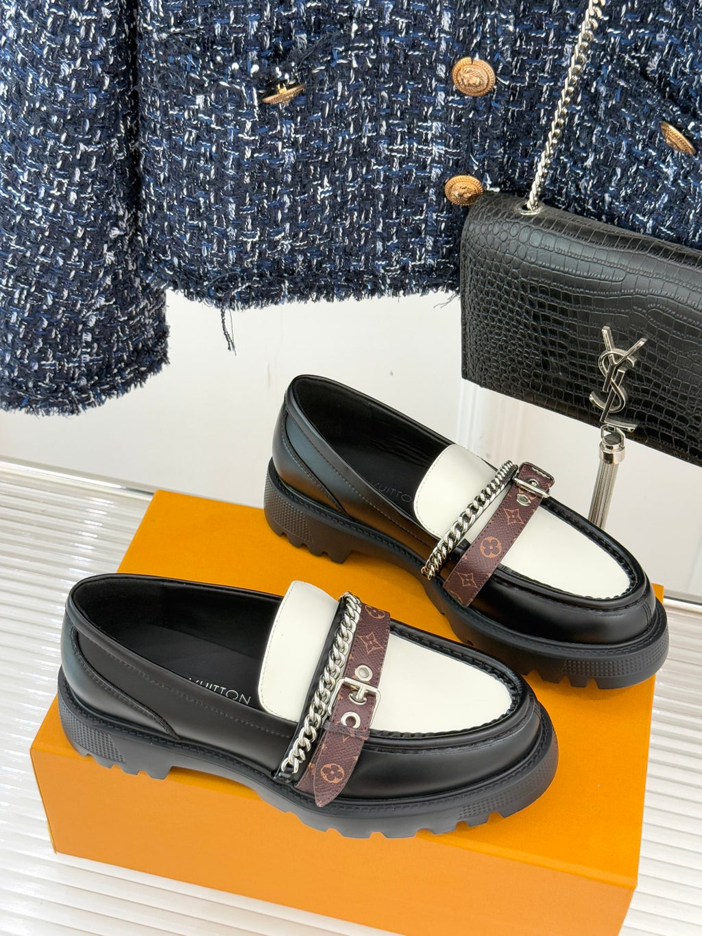 Black and white leather loafers with chain ornament and monogram strap on front