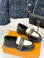 Black and white leather loafers with chain ornament and monogram strap on front