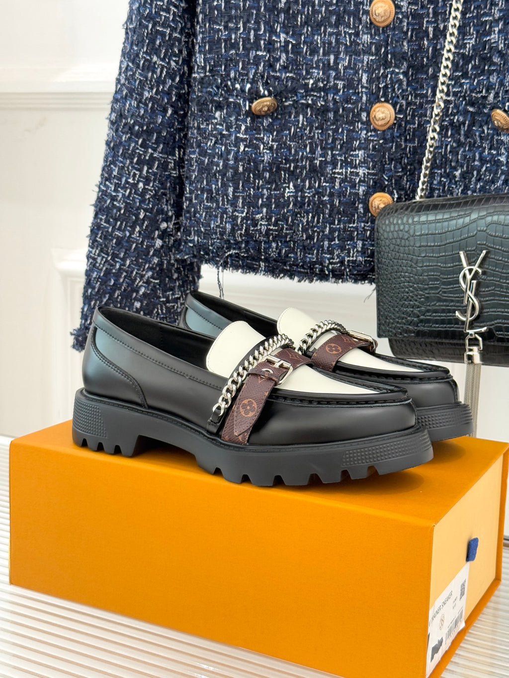 Black leather loafer with white upper panel, chain detail, and chunky tread sole
