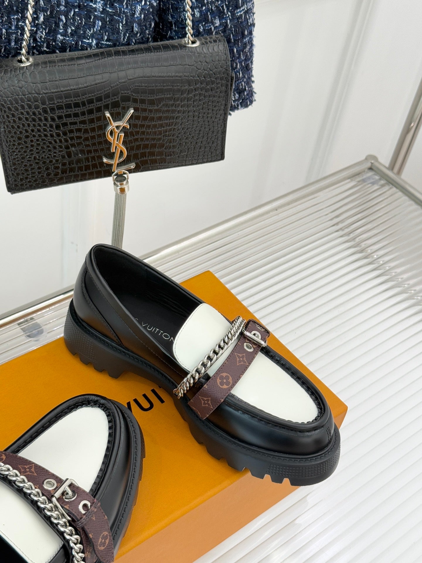 Black leather loafer with white vamp panel, chain detail, and monogram buckled strap