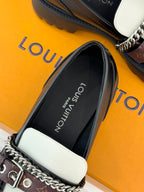 Close-up of black loafer interior label and white side panel with chain detail