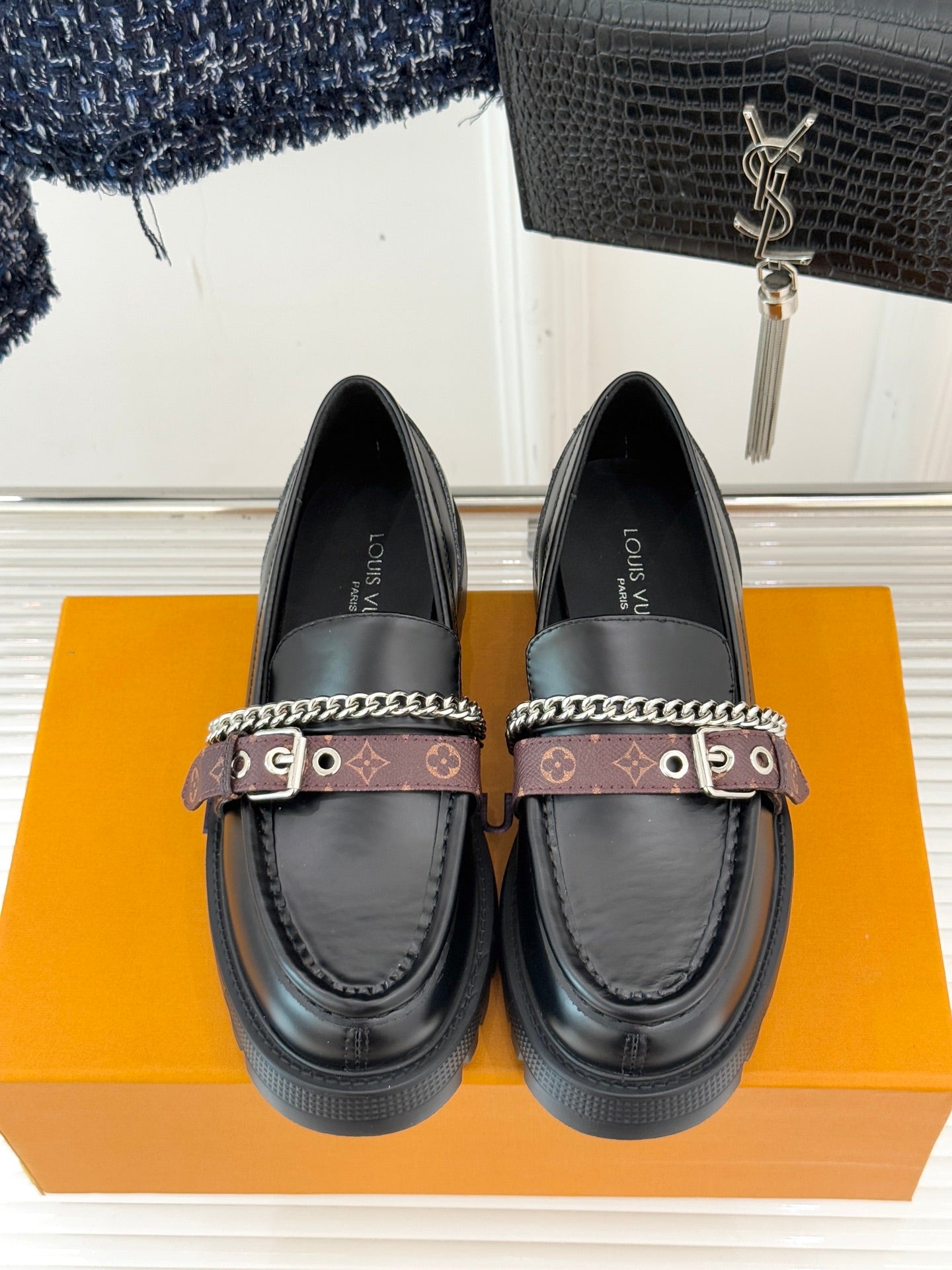 Black leather loafers with front buckle strap, chain detail, and platform sole