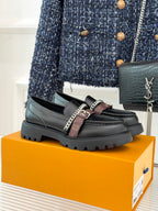 Black leather loafers with chain trim, monogram strap, and chunky platform sole