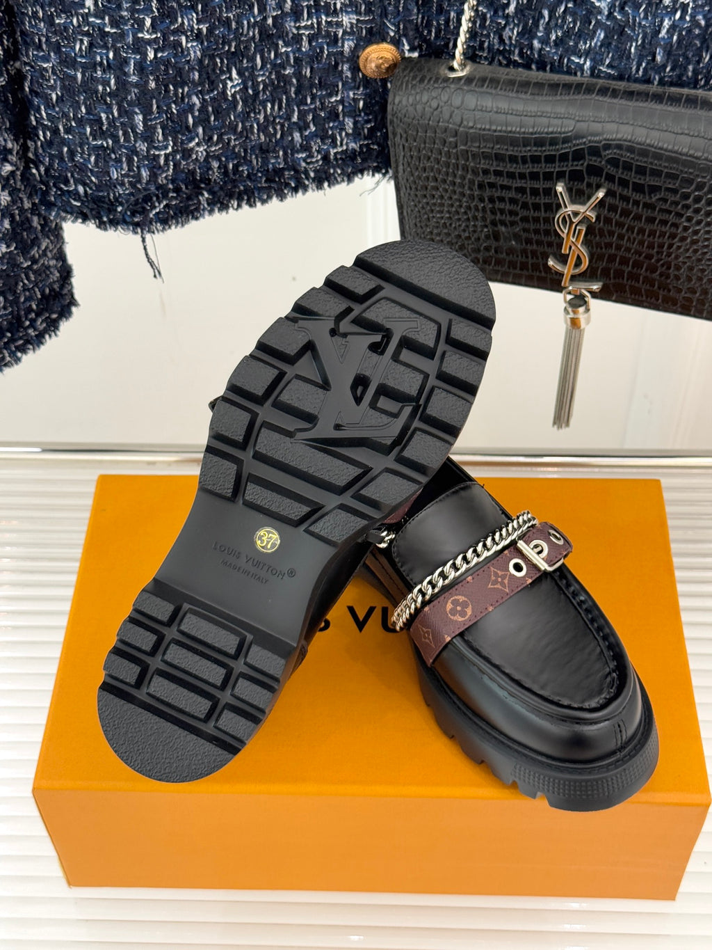 Black leather platform loafers showing tread sole and chain-trim strap