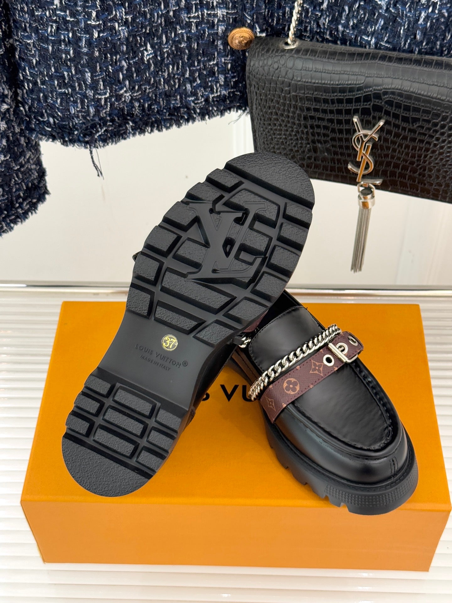 Black leather platform loafers showing tread sole and chain-trim strap