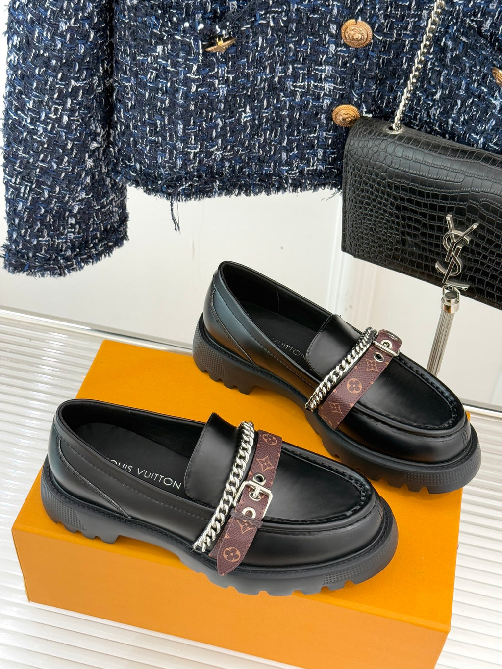 Black leather loafers with brown monogram strap, chain detail, and platform sole