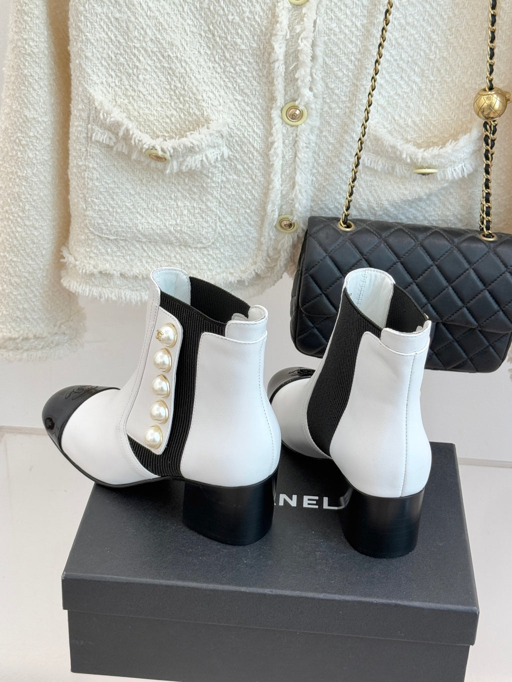 White ankle boots with black elastic inserts, pearl decoration, and matte black block heel