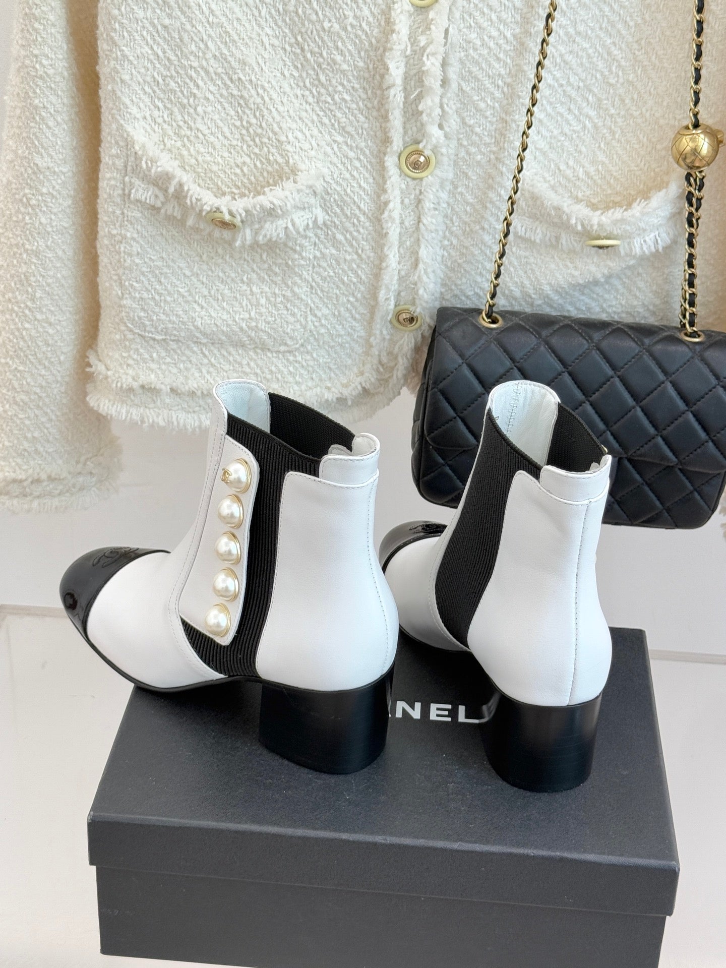 White ankle boots with black elastic inserts, pearl decoration, and matte black block heel