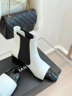 White ankle boots with black elastic side panel and glossy black toe cap on block heel