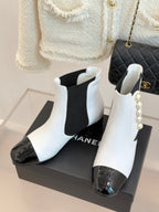 White Chelsea boots with black elastic panels, pearl trim, and black patent-style toe detail