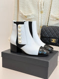 White ankle boots with black elastic sides, pearl embellishment, and black glossy toe caps