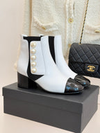 White ankle boots with black elastic sides, pearl embellishment, and black glossy toe caps