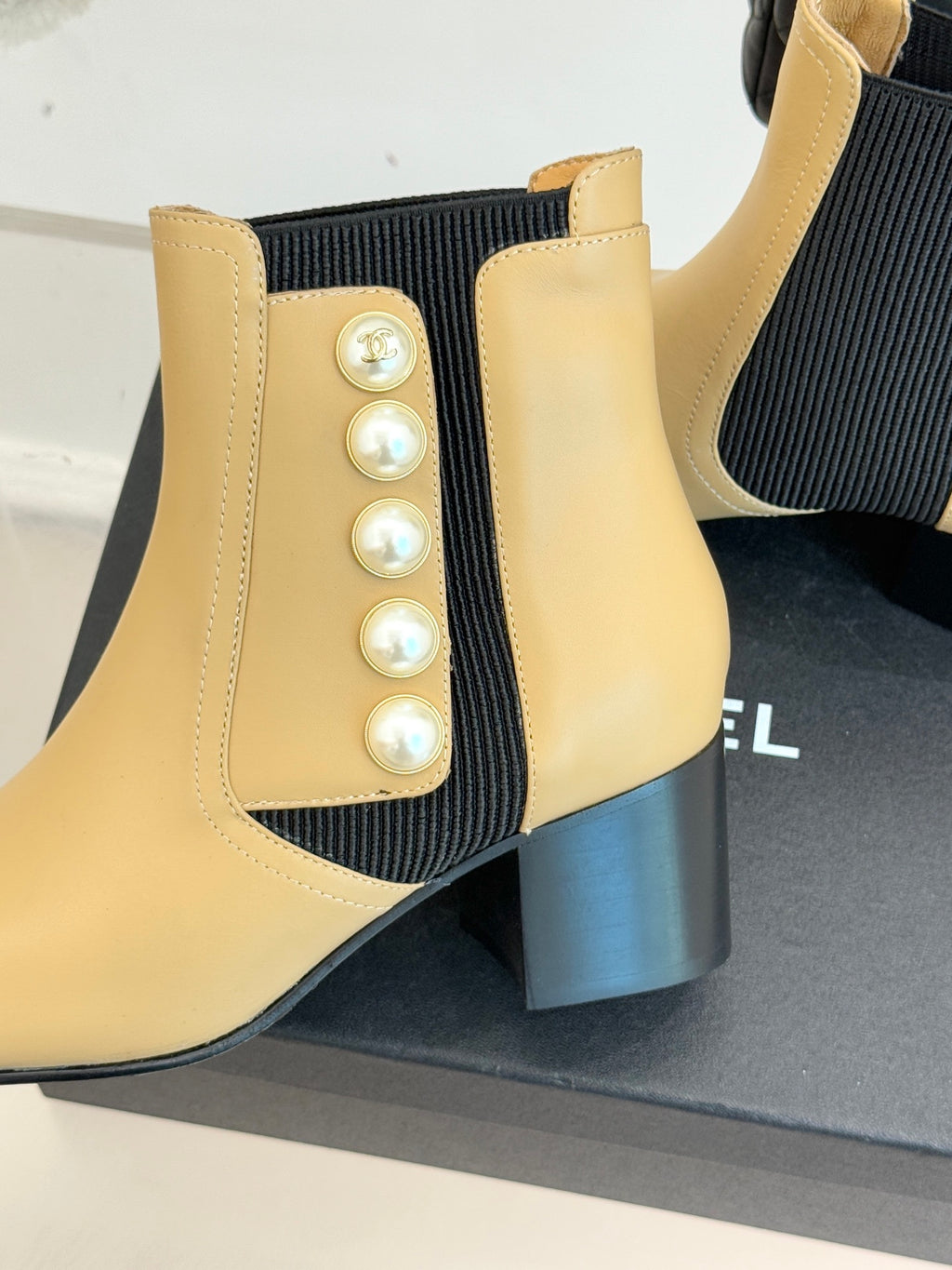 Chanel beige Chelsea boot close-up: pearl button detail on side with black stretch panel
