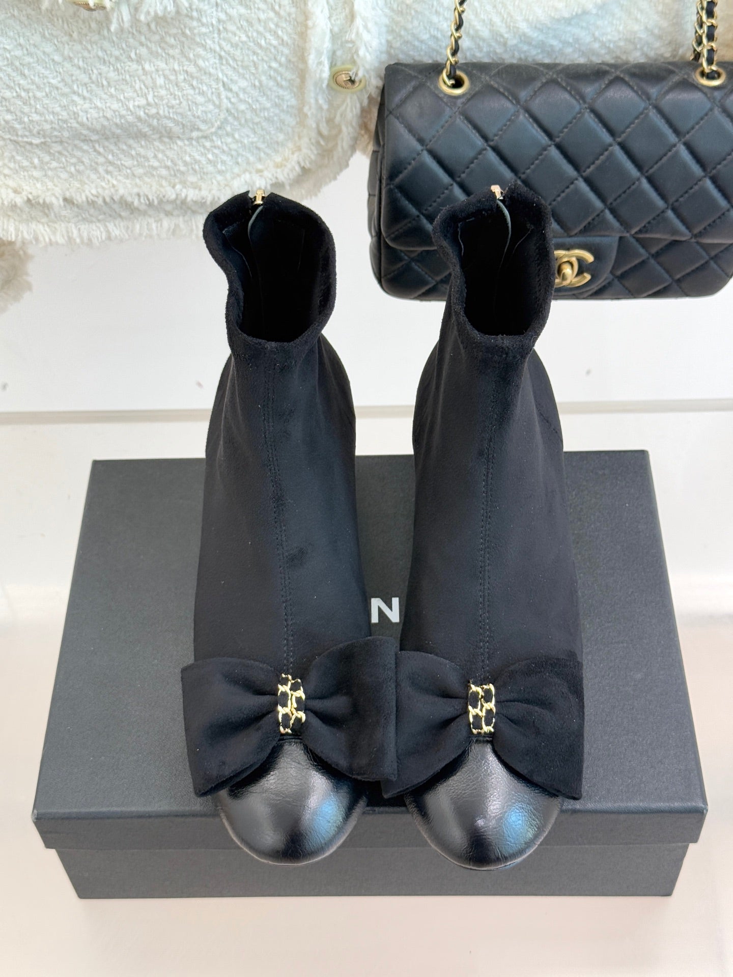 Chanel ladies ankle boots pair on display, bow accents and block heel, dark suede.