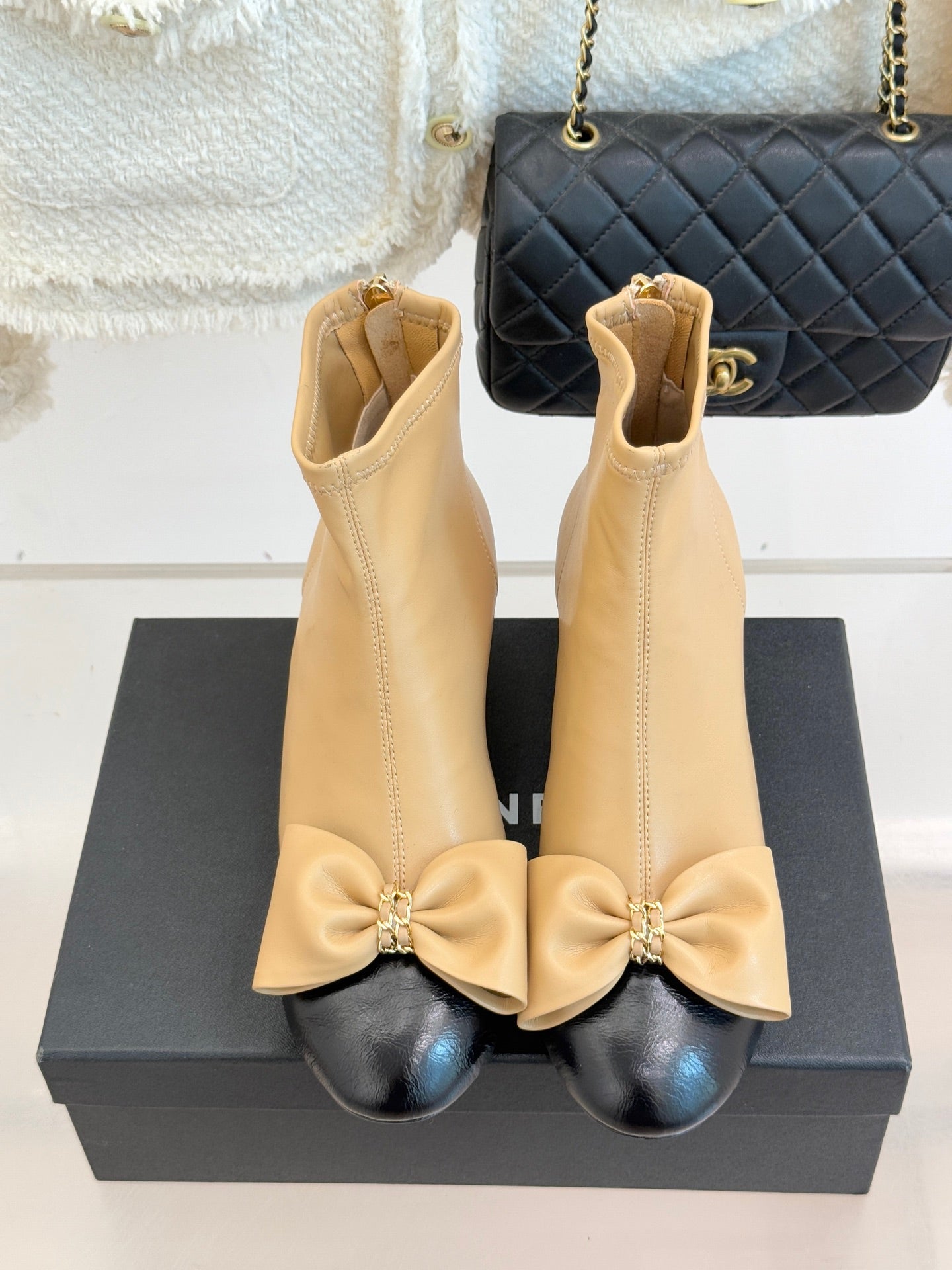 Pair of beige ankle boots with bow trim and side zip, block heel