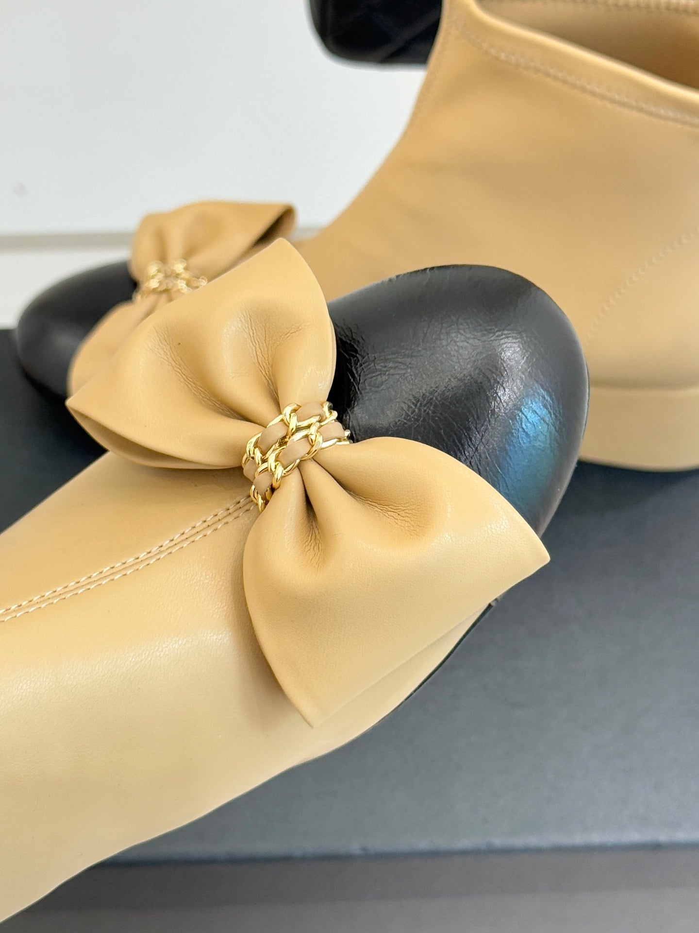 Beige ankle boot close-up with oversized bow and side zipper, textured leather