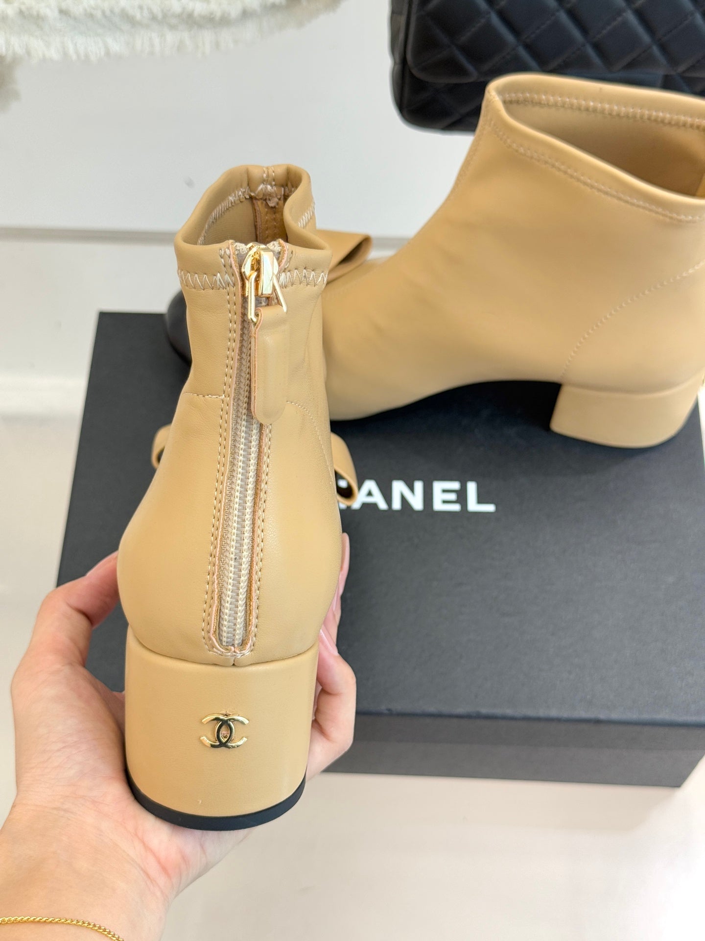 Beige ankle boot back view with side zip and CC logo emblem, block heel