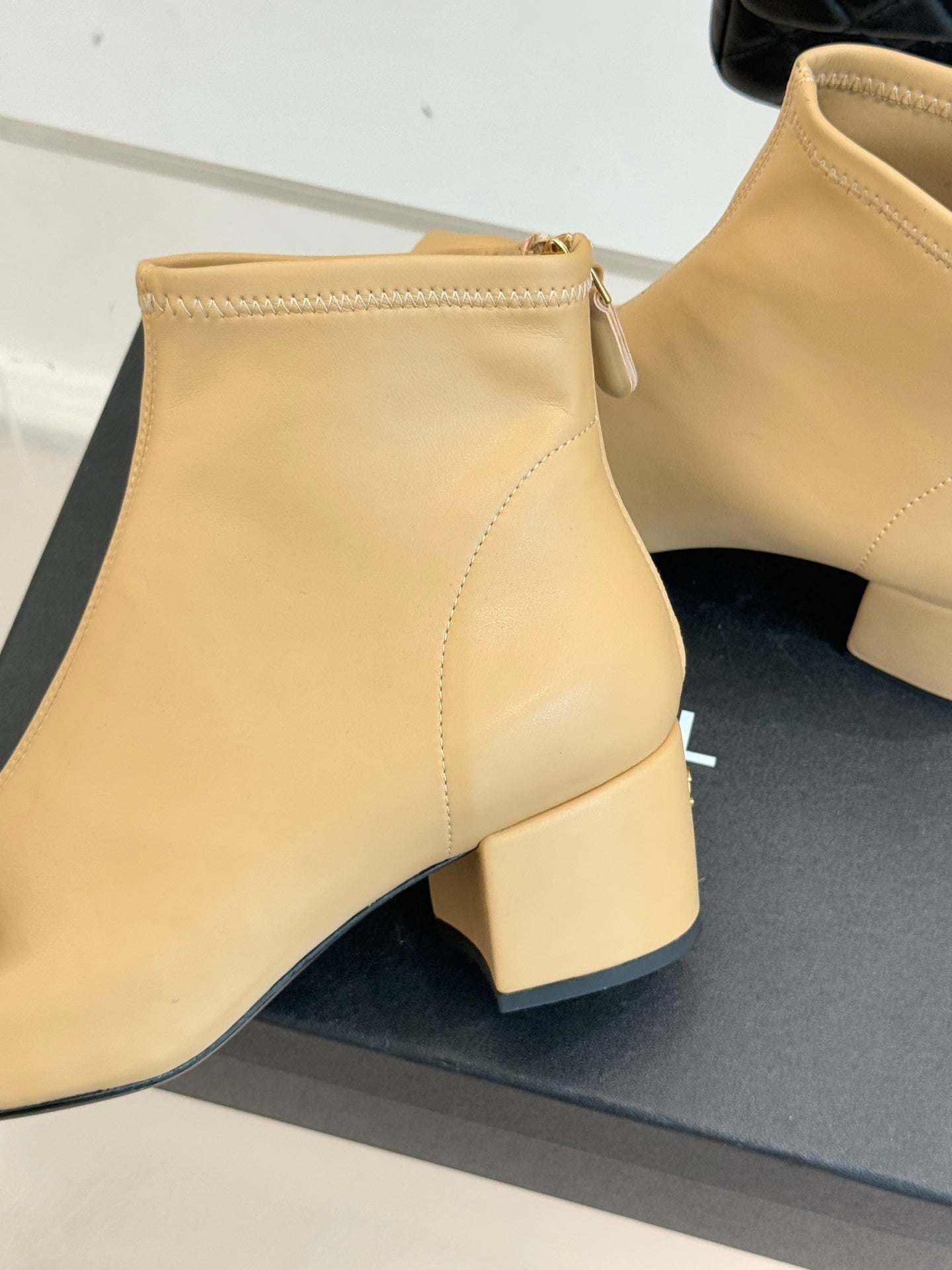 Beige ankle boot close-up with low block heel and side zipper, stitched seams