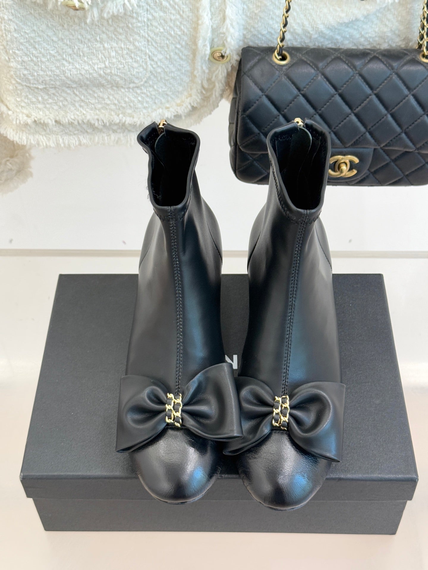Chanel dark navy leather ankle boots with block heel and bow accents, back view