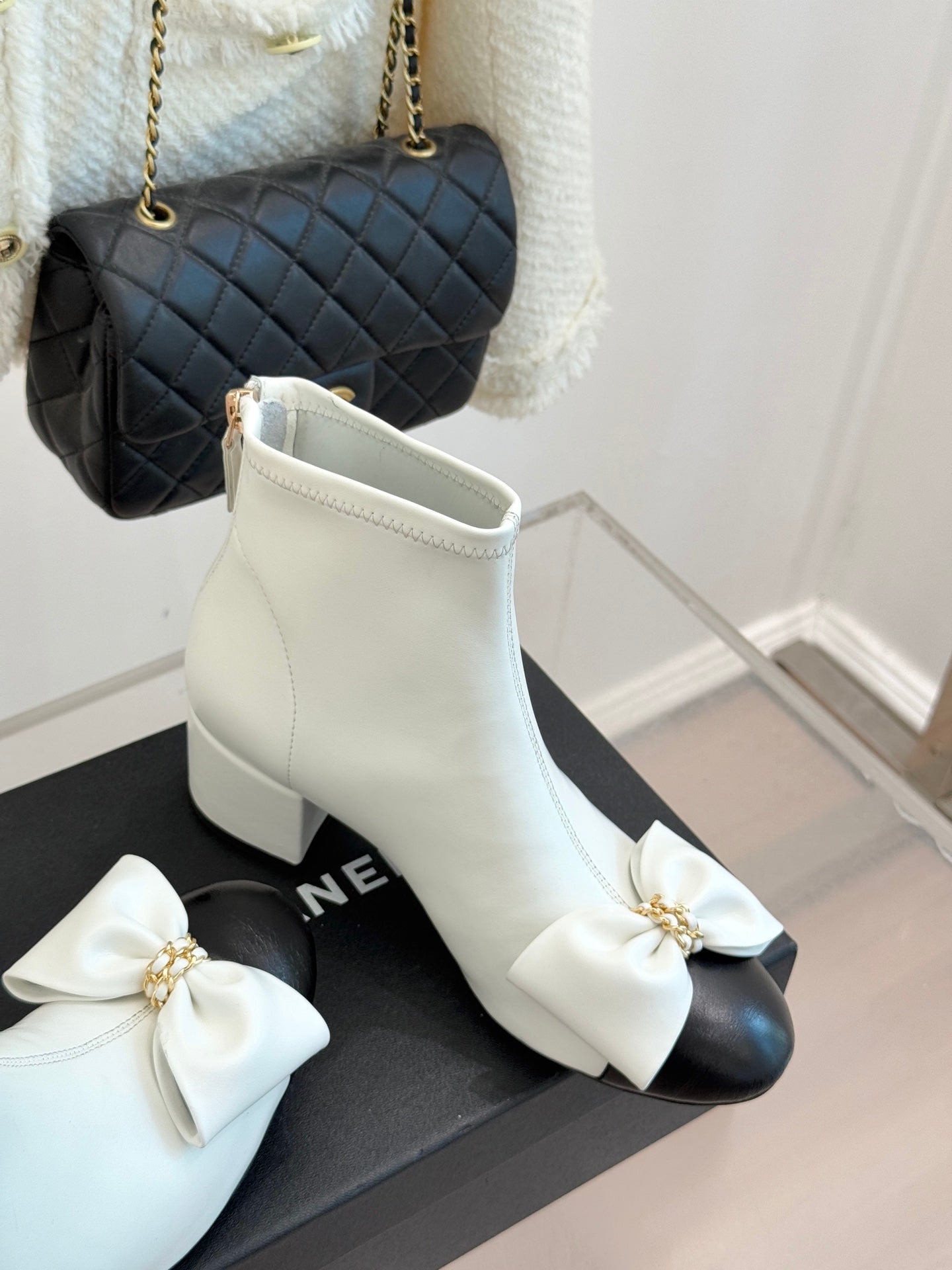 White ankle boot with side zipper and large bow embellishment on toe