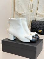 White ankle boots with bow accent and block heel, gold-tone hardware on cuff