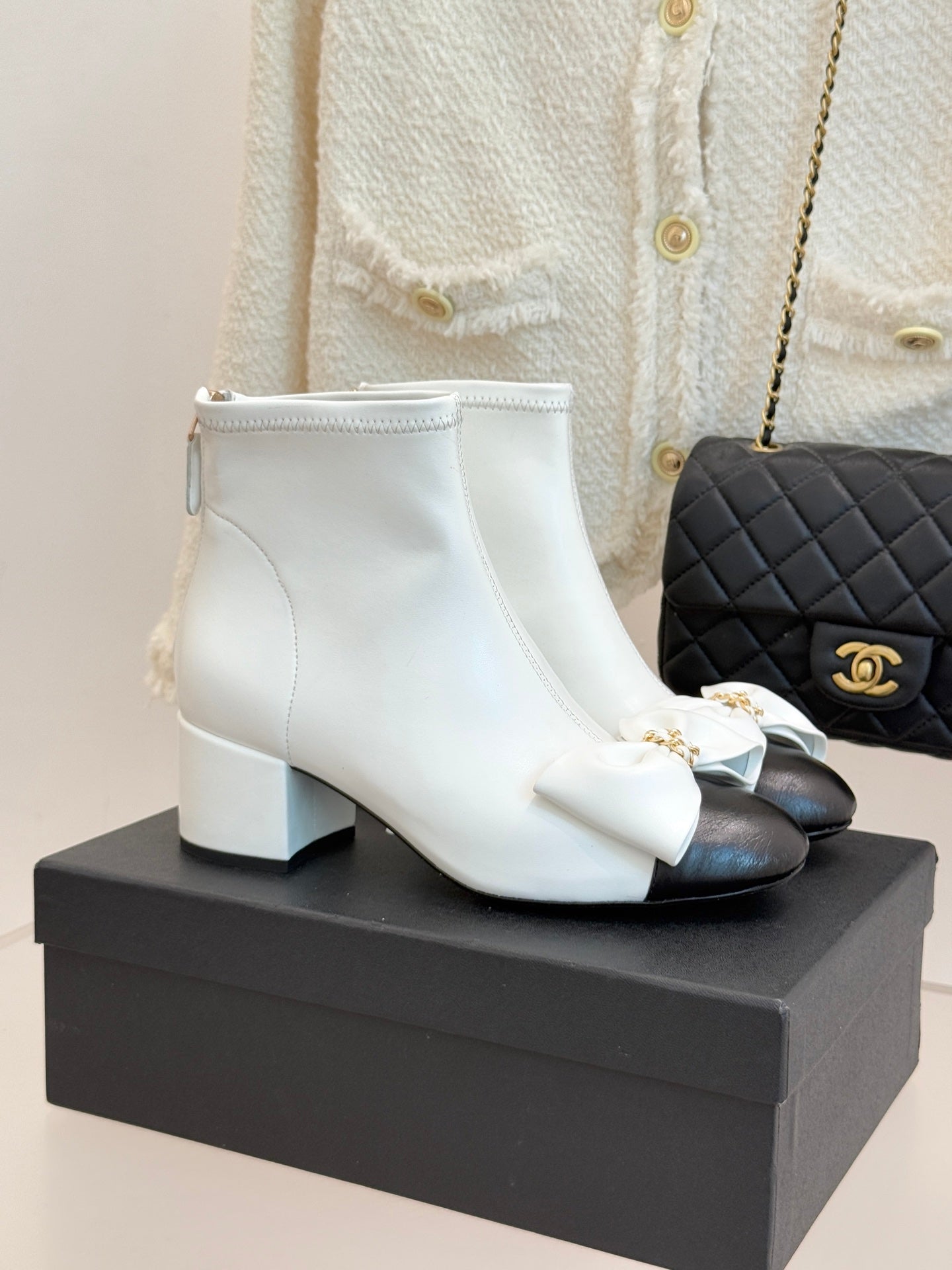 White ankle boots with bow accent and block heel, gold-tone hardware on cuff