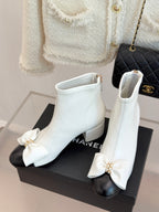 Pair of white ankle boots with front bow detail, side zipper and block heel