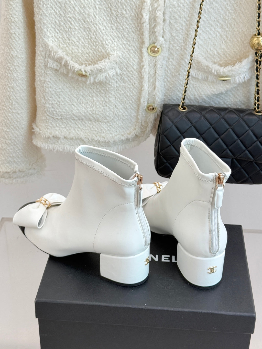 White ankle boots with gold-tone zipper pull and bow detail on front