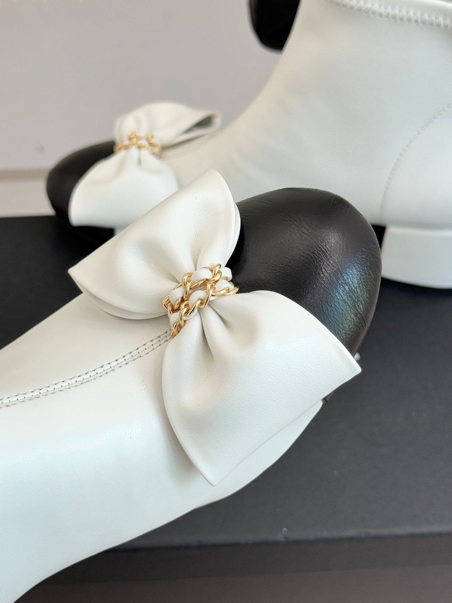 White ankle boot toe with oversized bow and gold-tone chain detail