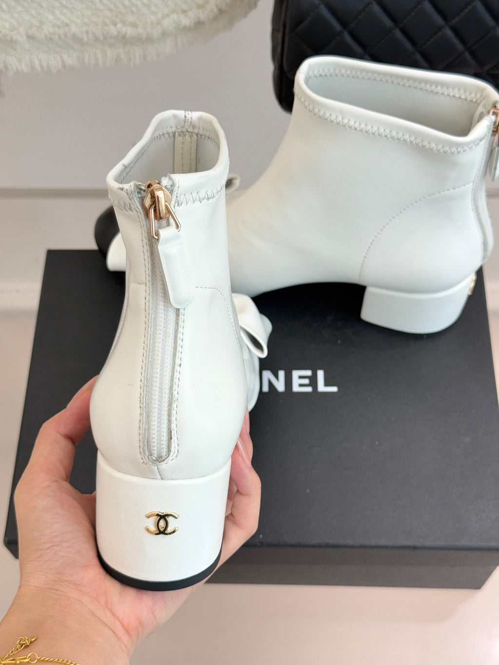 White ankle boots rear view with heel, side zipper and gold-tone logo patch