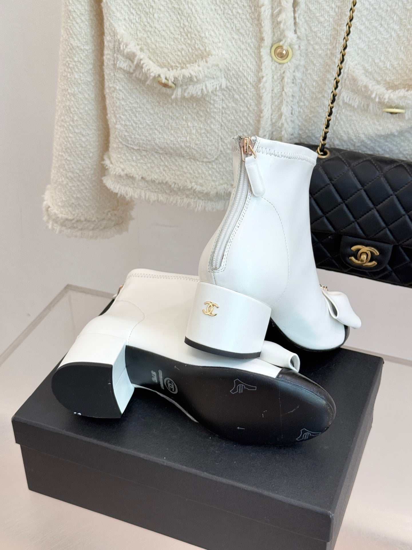 White ankle boots on box, featuring bow detail and side zipper