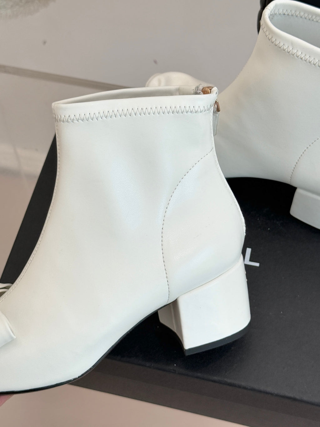 Close-up of white ankle boot shaft with stitching and block heel