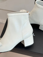 Close-up of white ankle boot shaft with stitching and block heel