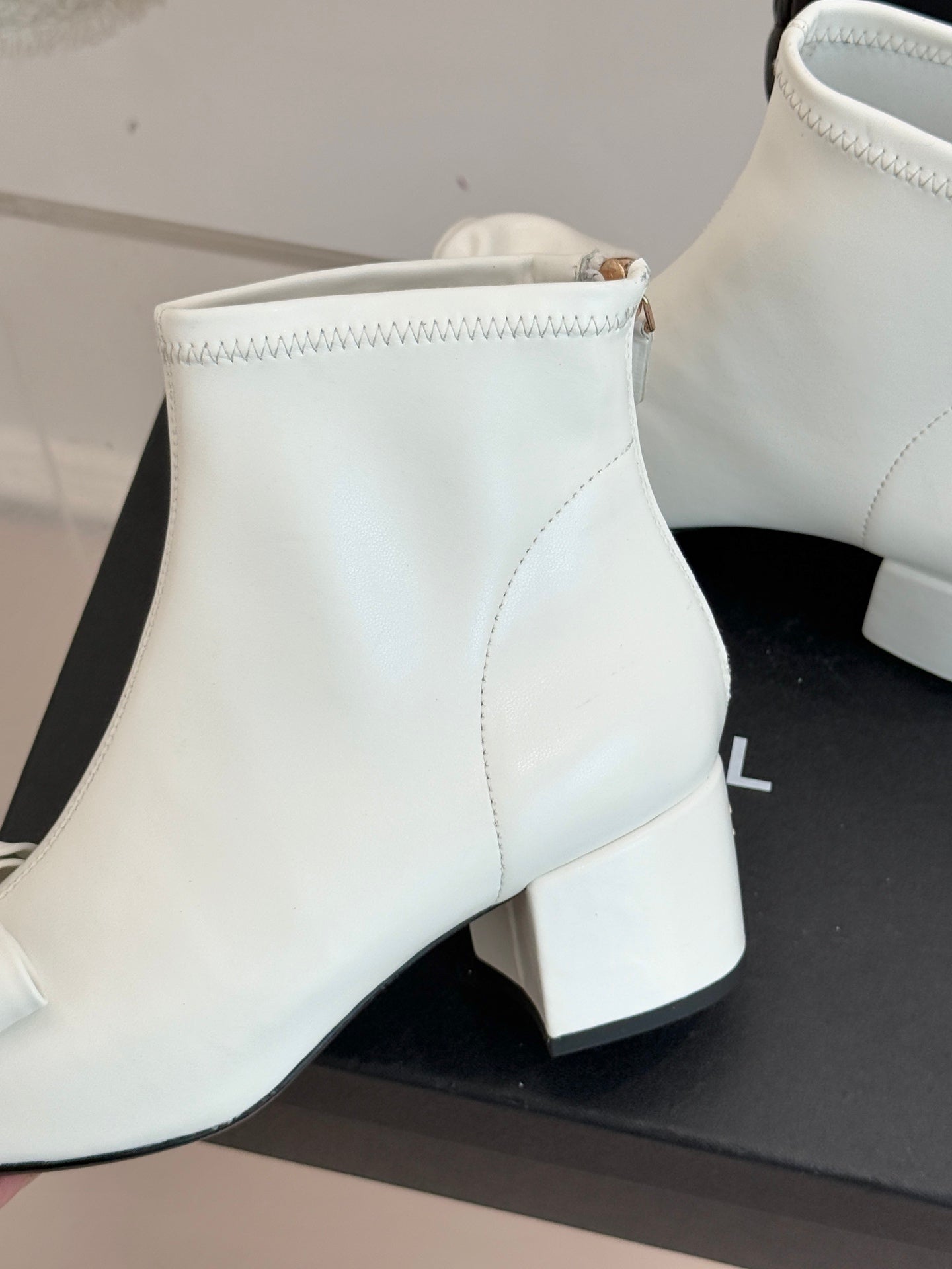 Close-up of white ankle boot shaft with stitching and block heel