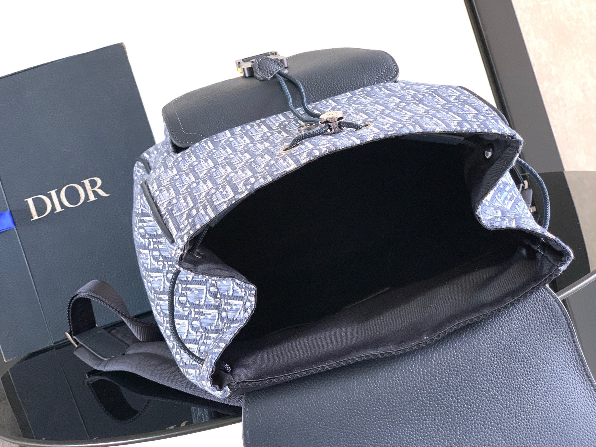 Dior backpack open view showing black interior and blue-and-white monogram jacquard.
