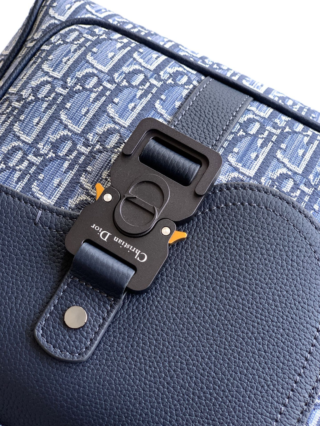 Men's Dior backpack clasp detail on blue leather flap with engraved hardware