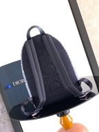 Dior mini backpack back view in dark blue with padded straps and top handle