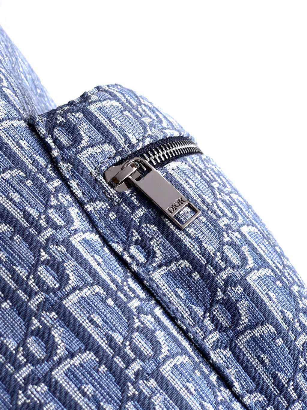 Dior men’s backpack zipper pull with metal tag on light blue monogram fabric
