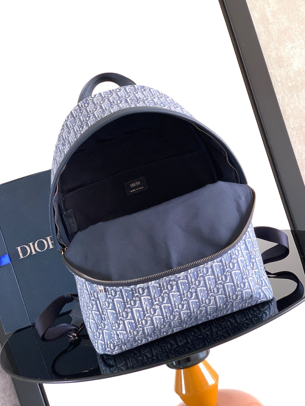 Dior men’s backpack open top showing dark interior pocket lining and blue monogram