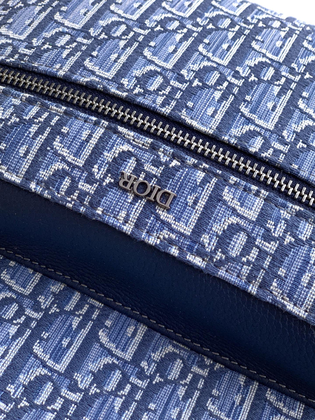 Dior men’s backpack close-up of zip track on blue patterned fabric with Dior text