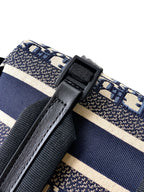Dior backpack side close-up with black strap tab and blue/cream striped webbing