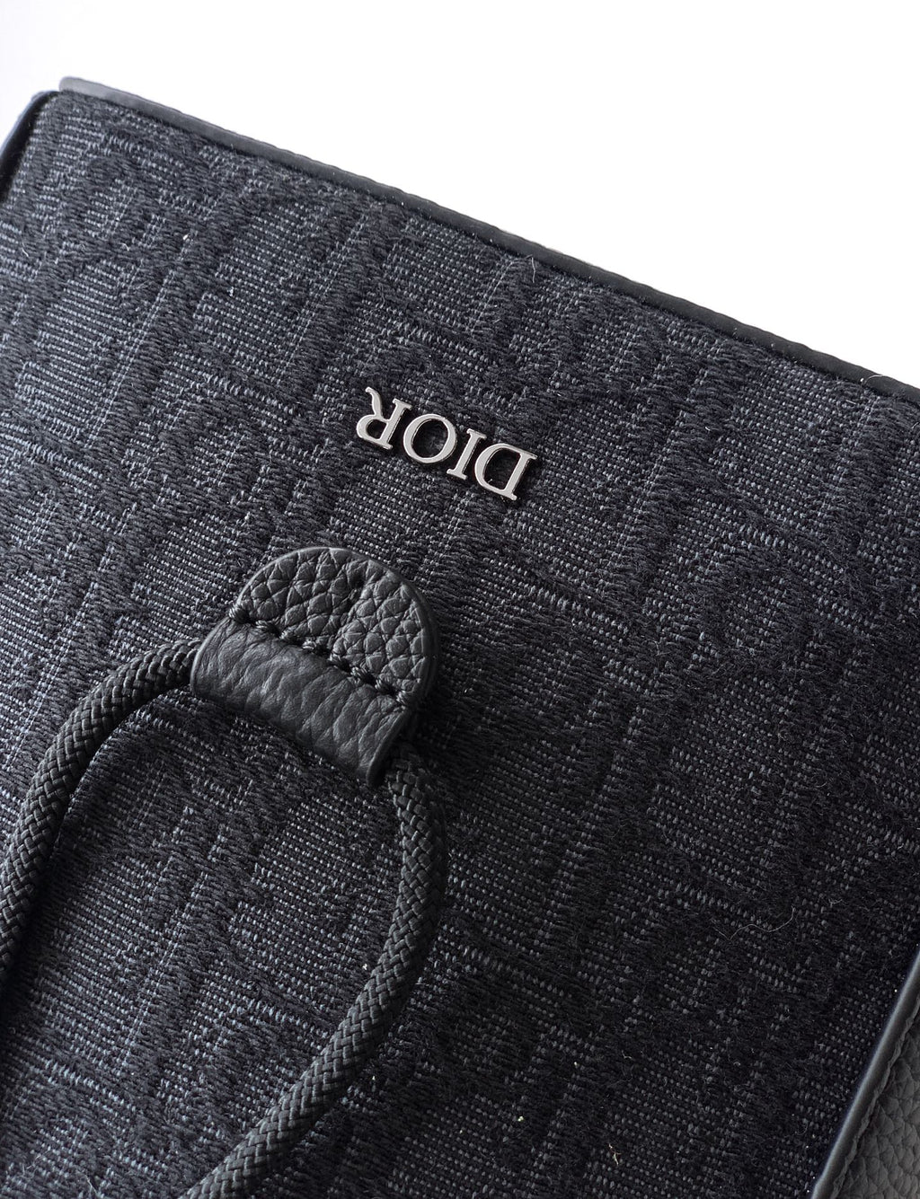 Dior logo fabric tag on dark pouch with leather snap tab