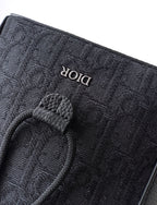 Dior logo fabric tag on dark pouch with leather snap tab