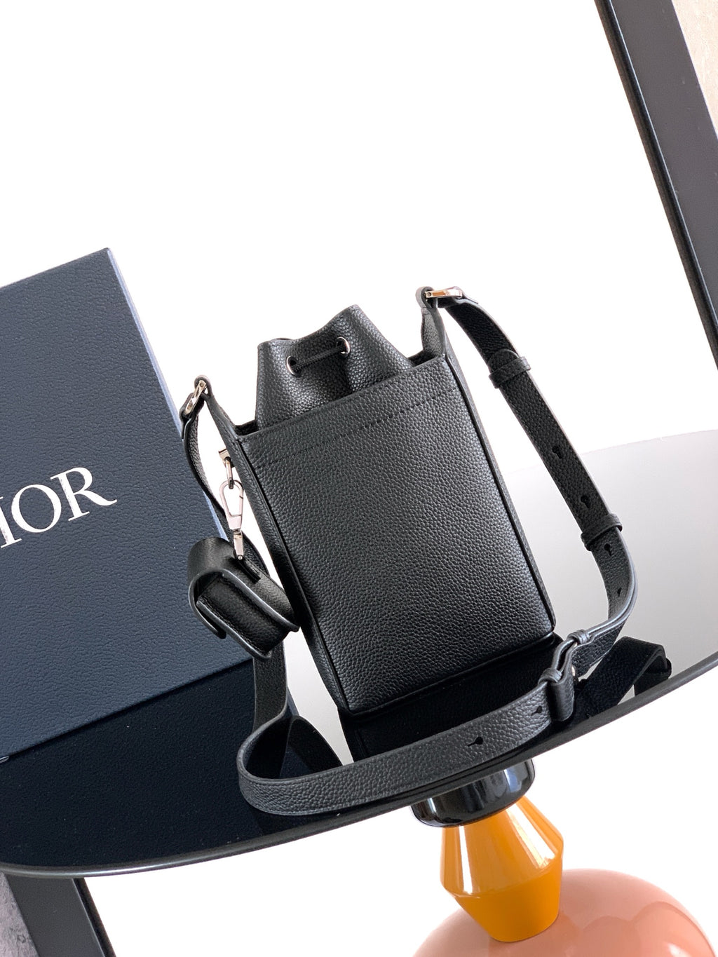 Black leather mini bag with top handle, front buckle straps, and crossbody strap