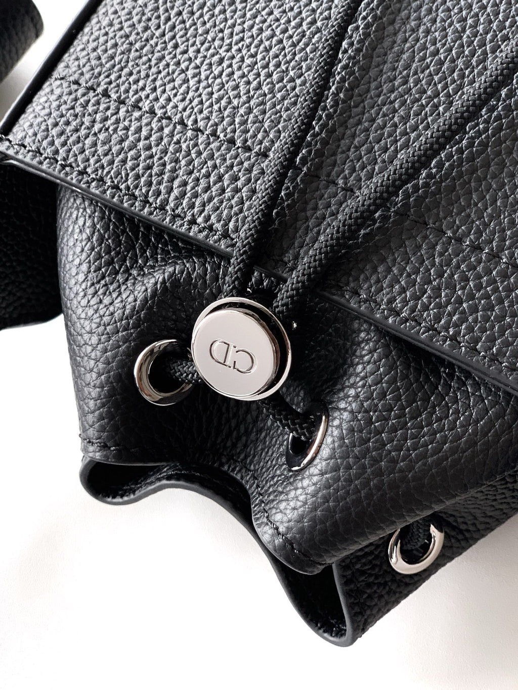 Black leather bag close-up with snap button hardware and textured grain