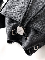 Black leather bag close-up with snap button hardware and textured grain