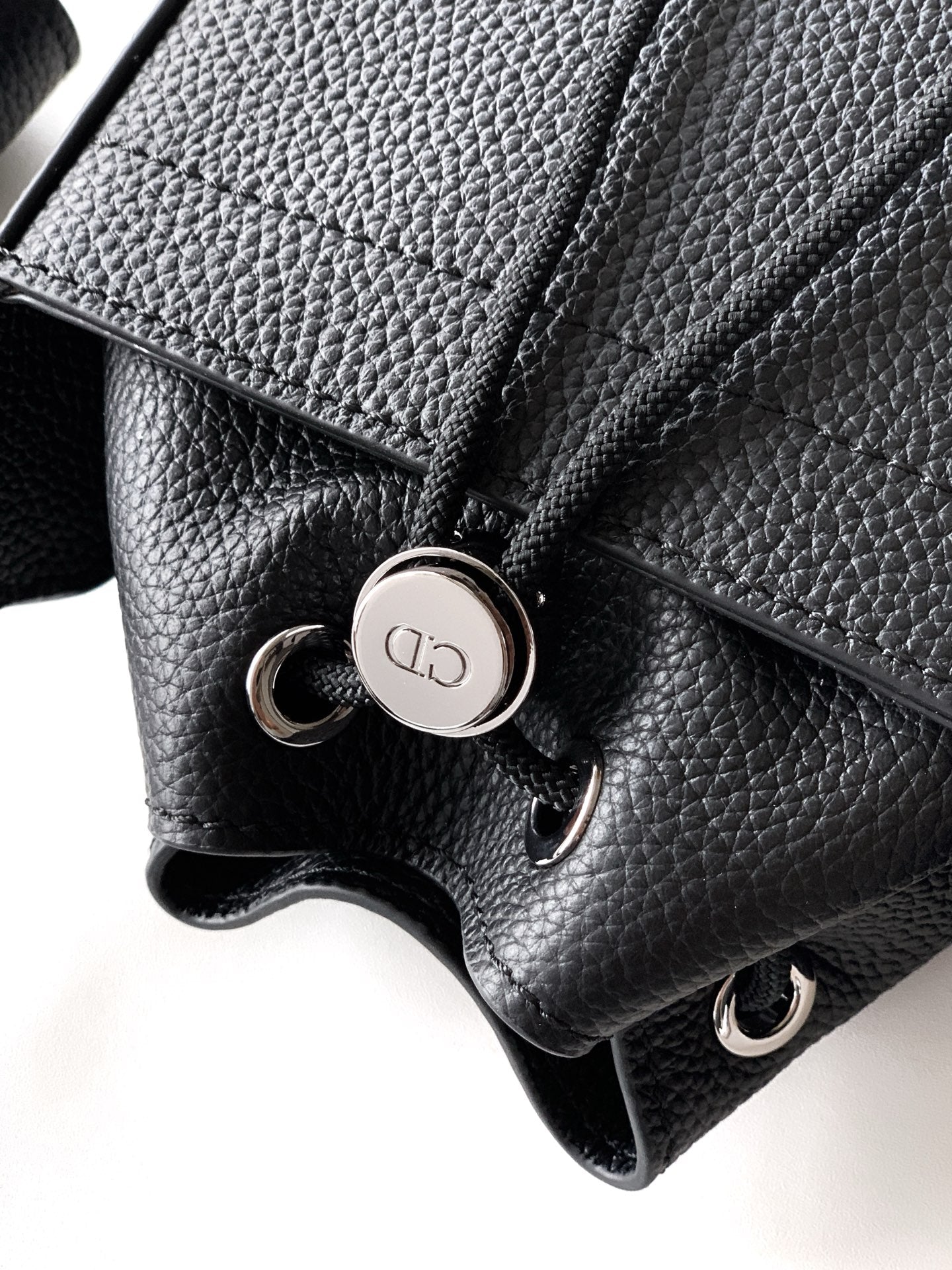 Black leather bag close-up with snap button hardware and textured grain